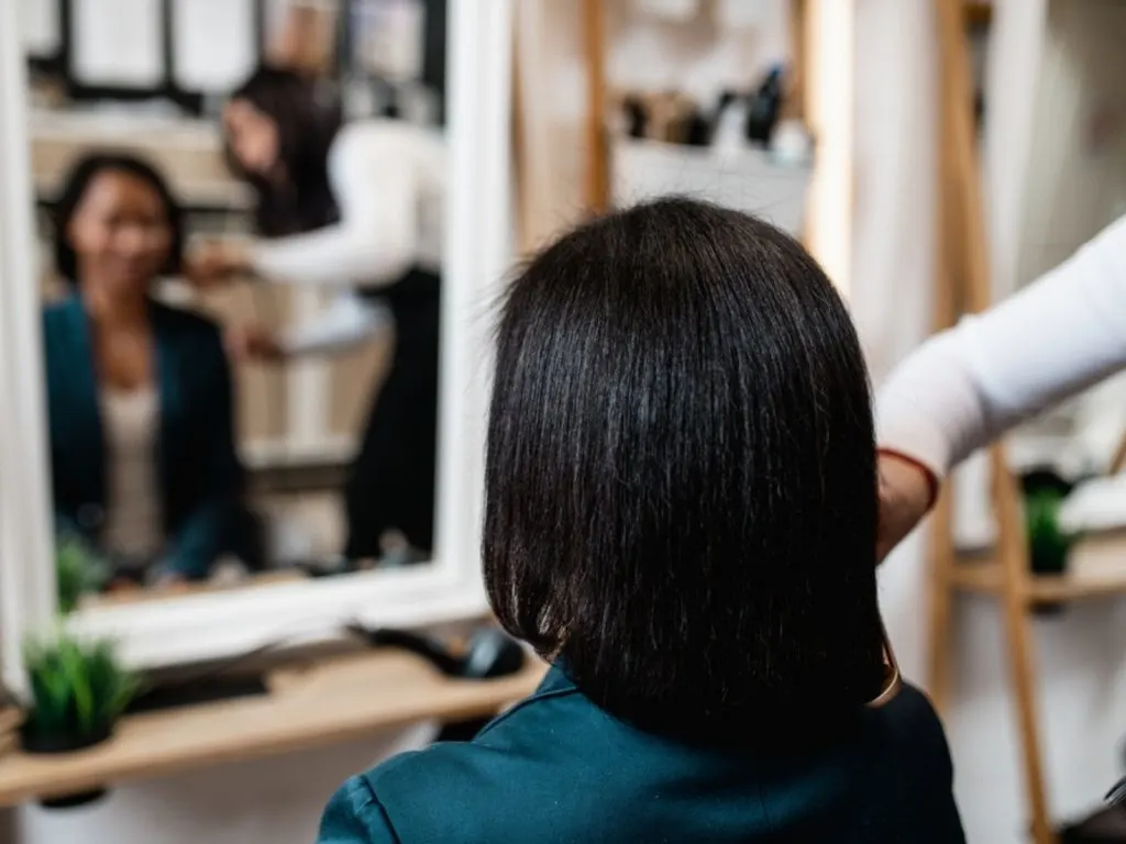 woman having hair straightened at the salon