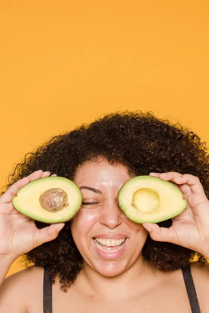 woman holding avocados on her face