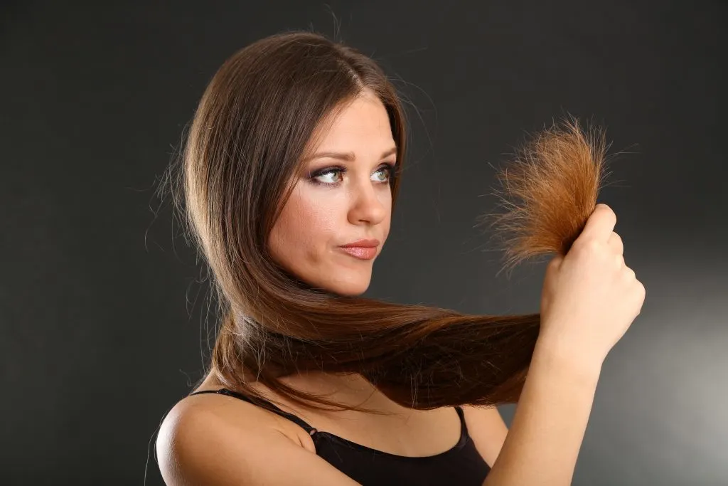 woman looking at split ends on long hair