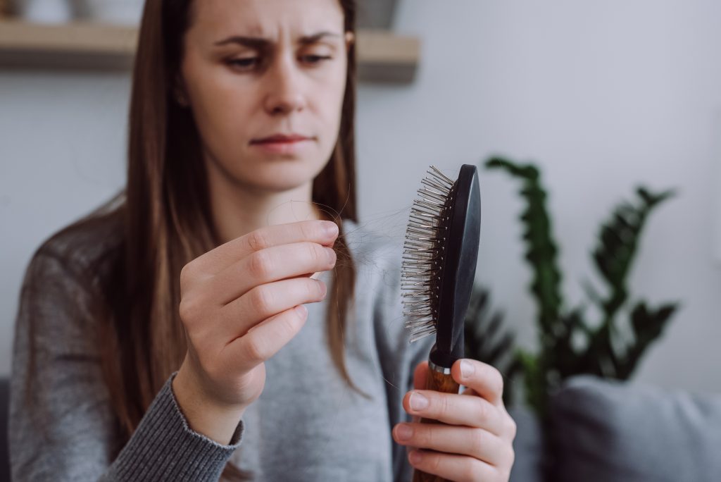 woman looking at strand of hair on brush