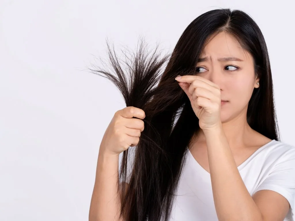 woman looking at the split ends in her hair