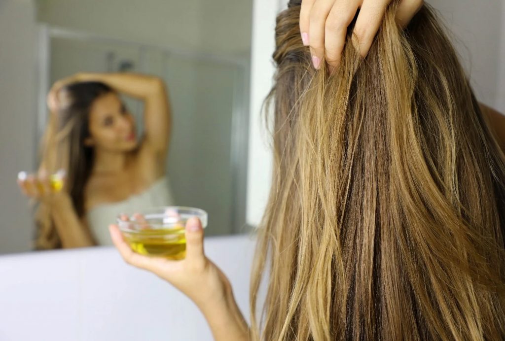 mujer aplicándose aceite capilar en el cuero cabelludo