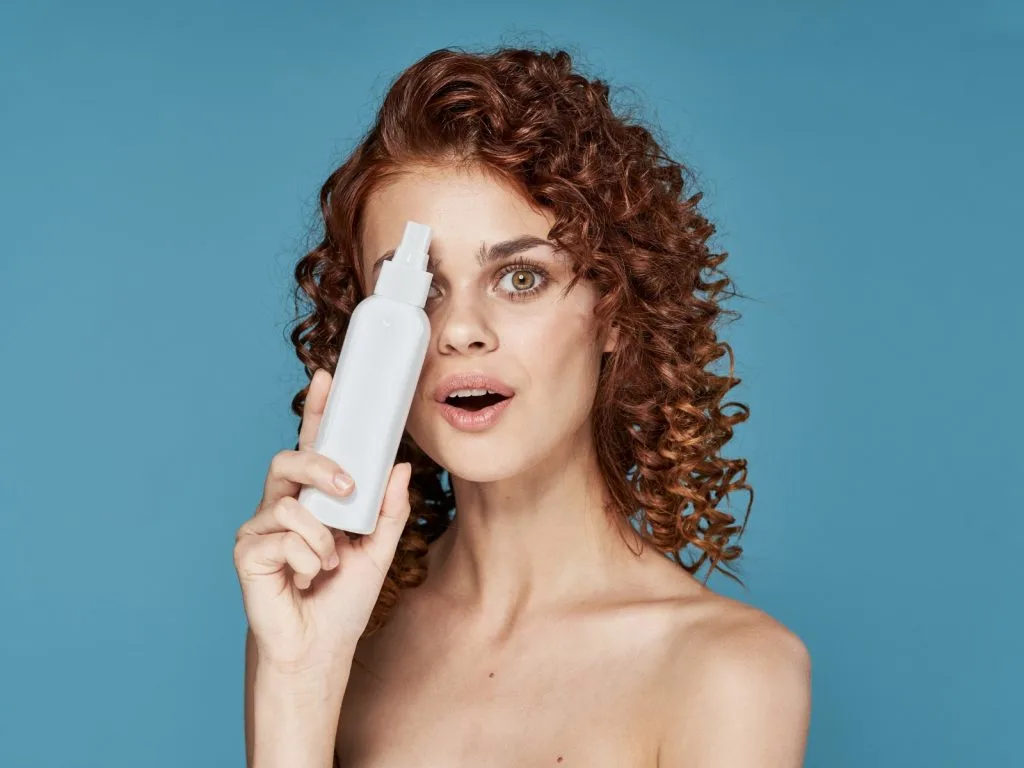 woman with curly hair holding hair product