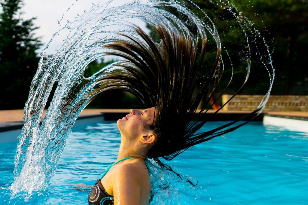 mujer revolviendose el pelo en la piscina