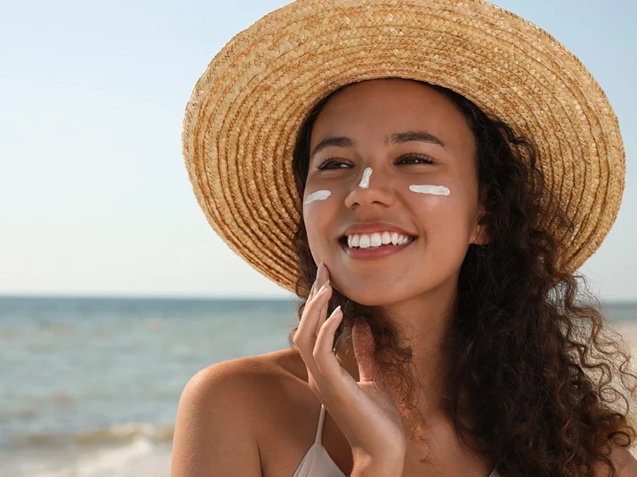 femme portant un chapeau de soleil et de la crème solaire