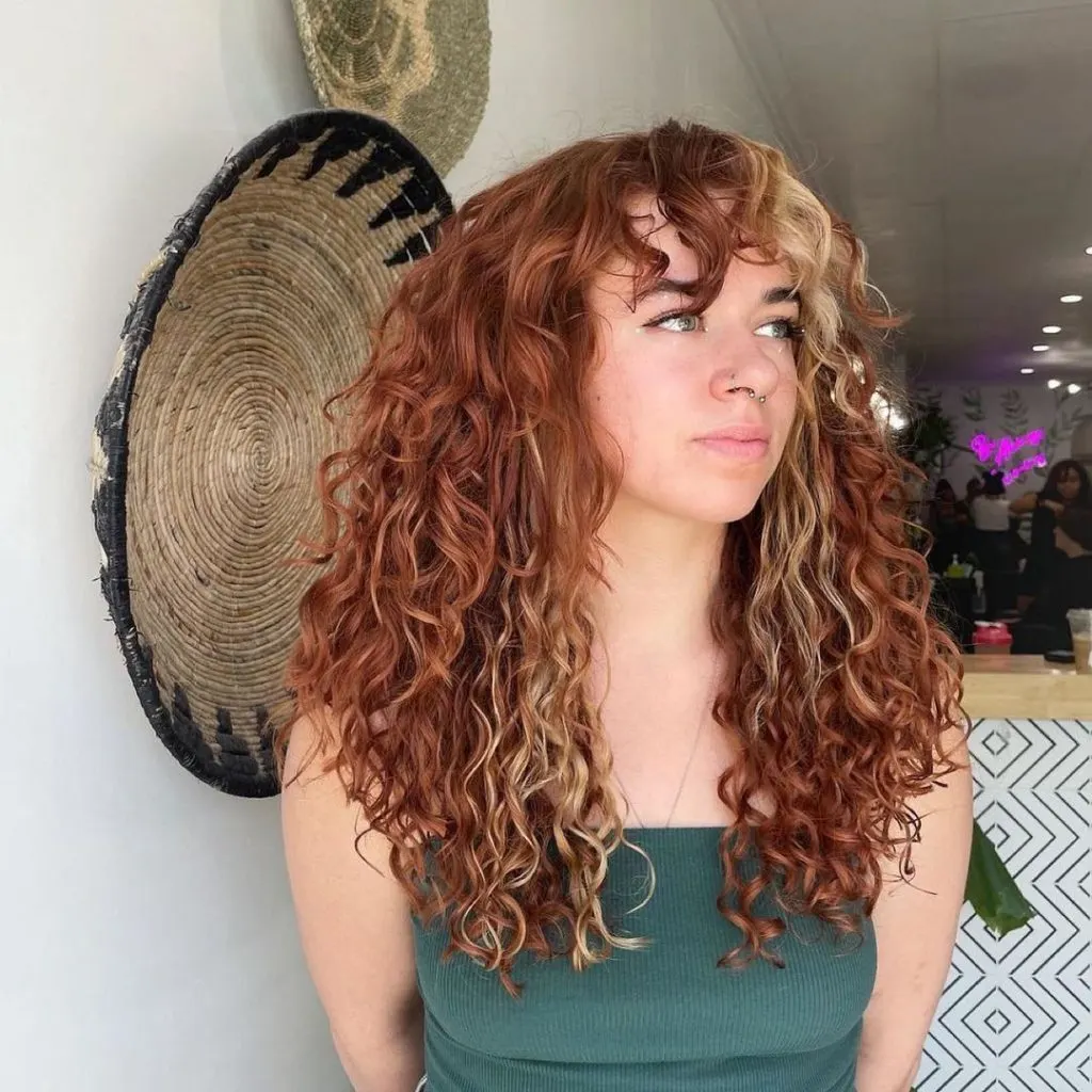 a young woman with blonde copper color blocking for long curly hair