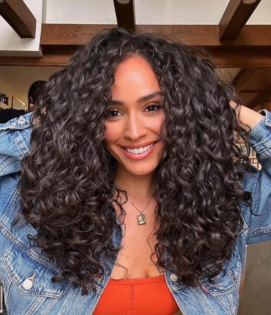 a woman with a coffee black long layered curly hair
