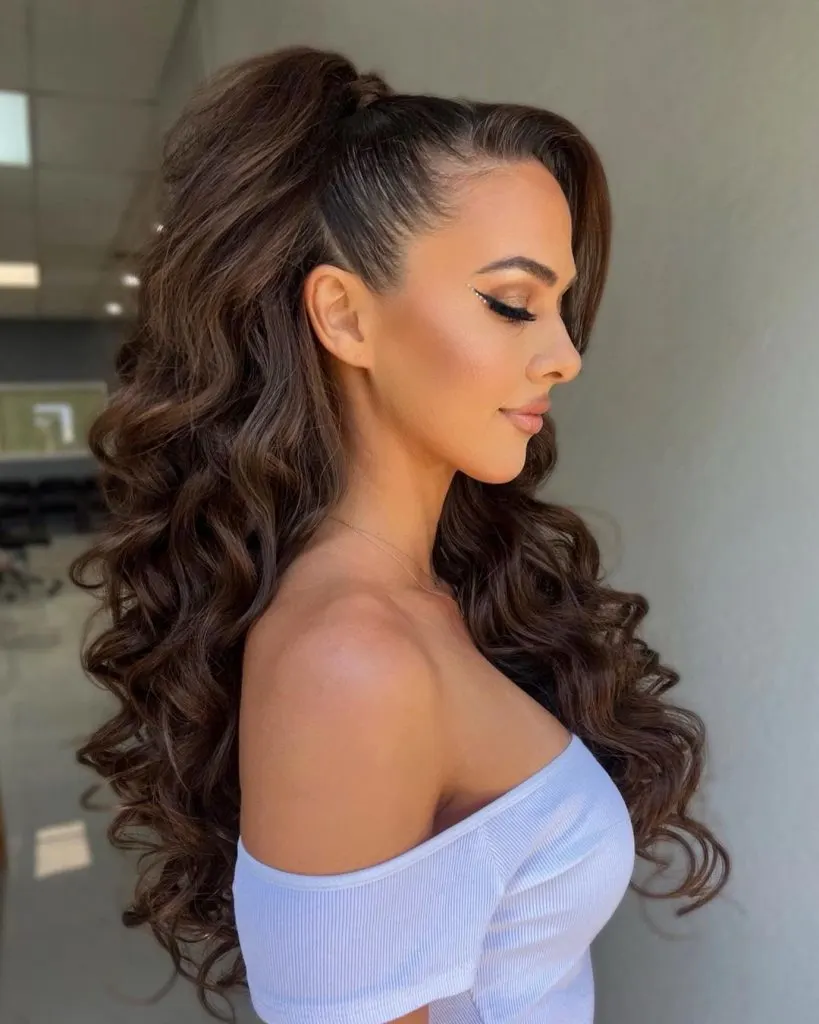 a young woman with a long wavy side parted hairstyle and a slicked back ponytail