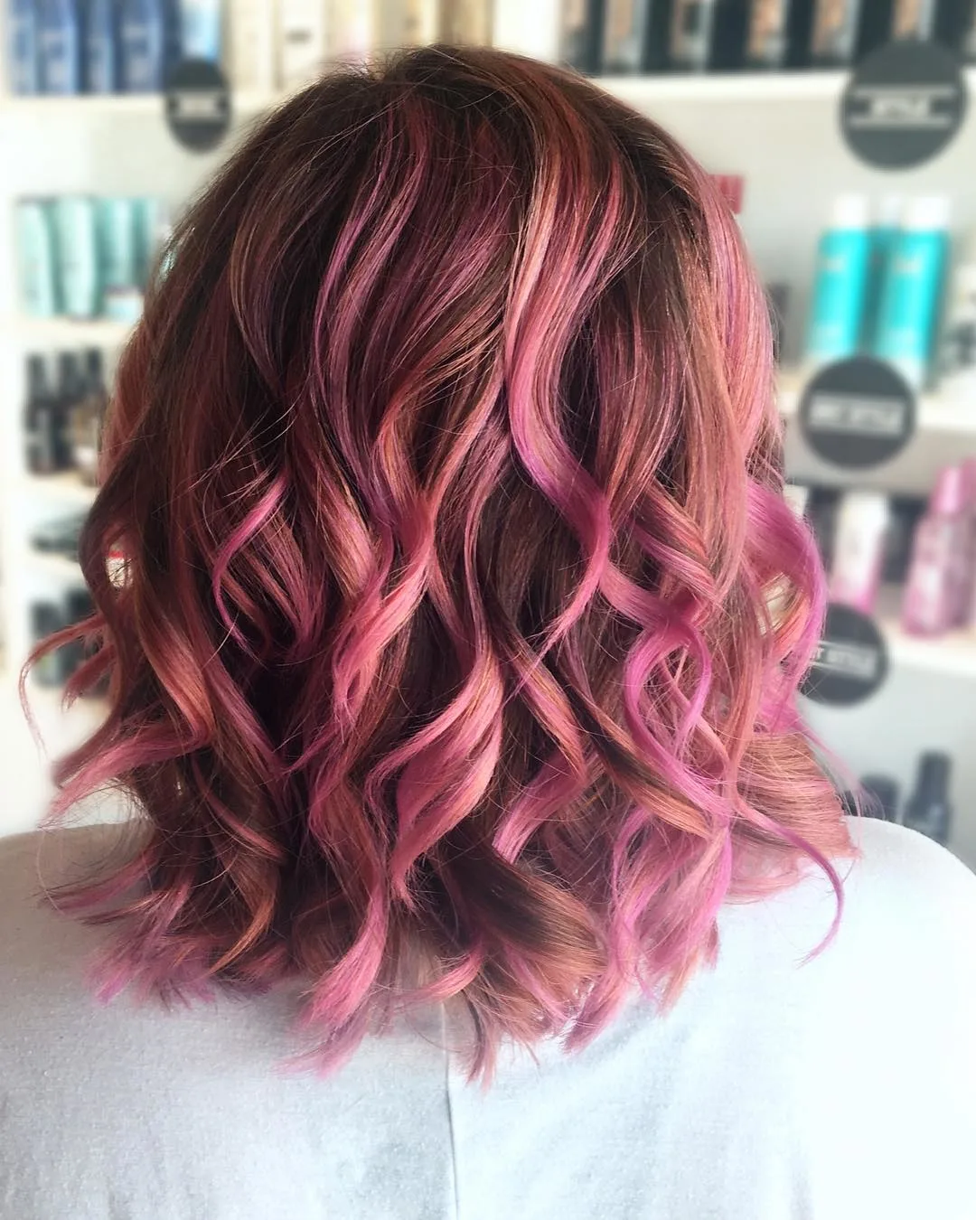 medium length copper waves with pink highlights hairstyle photographed from behind