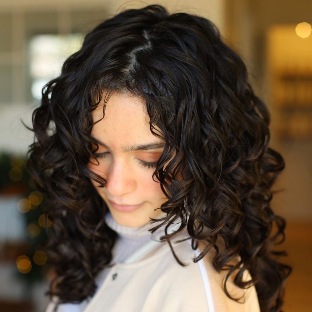 a girl with medium length curls and zig zag parting looking down