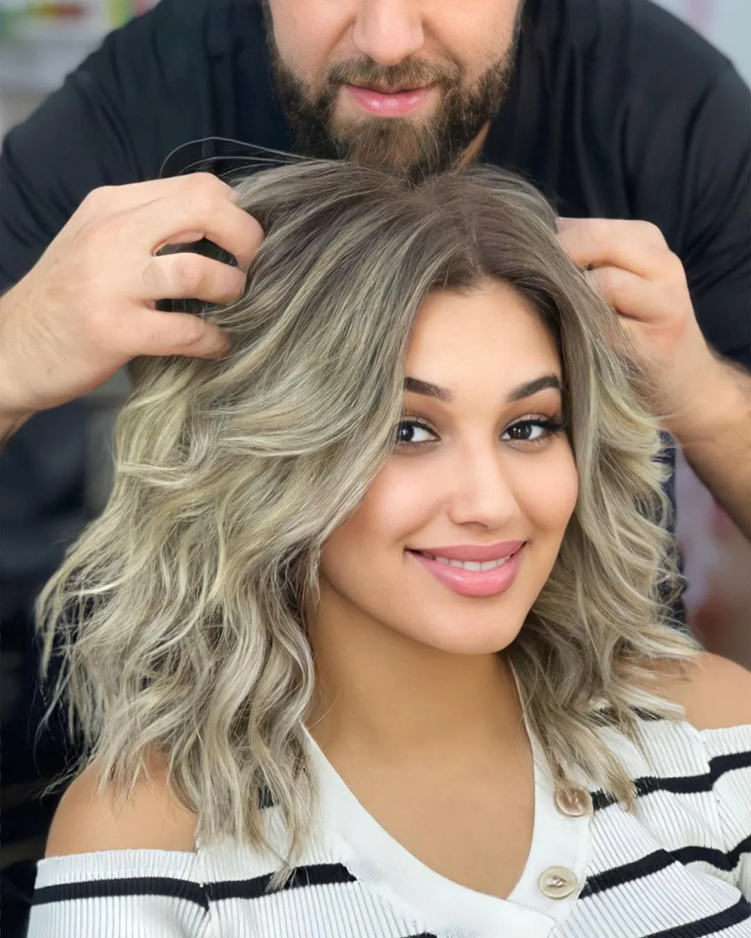 a woman with mid length ash blonde balayage waves smiling