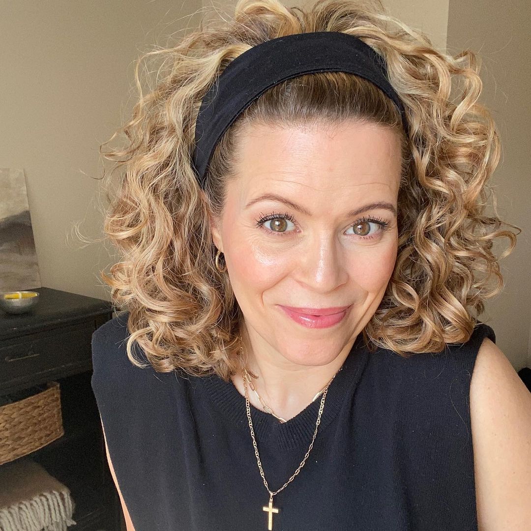 a woman with mid-length highlighted curls and a headband 
