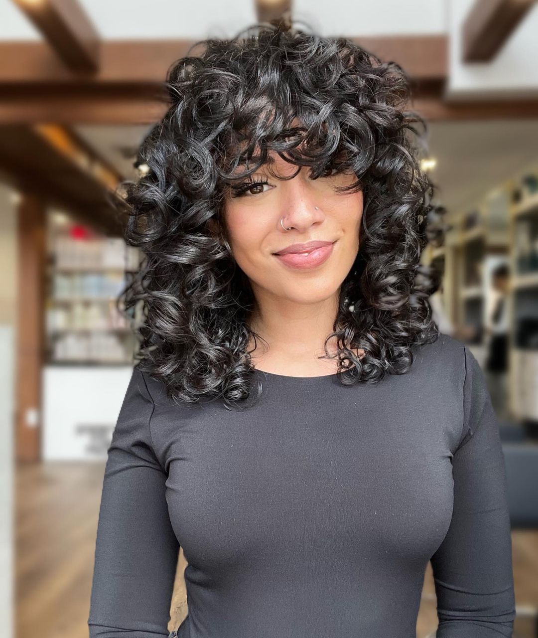 a woman with shoulder length loose curls and bangs