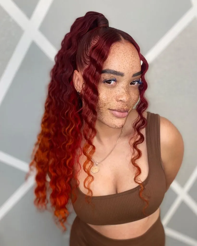 a woman with a slicked back high ponytail in copper tones