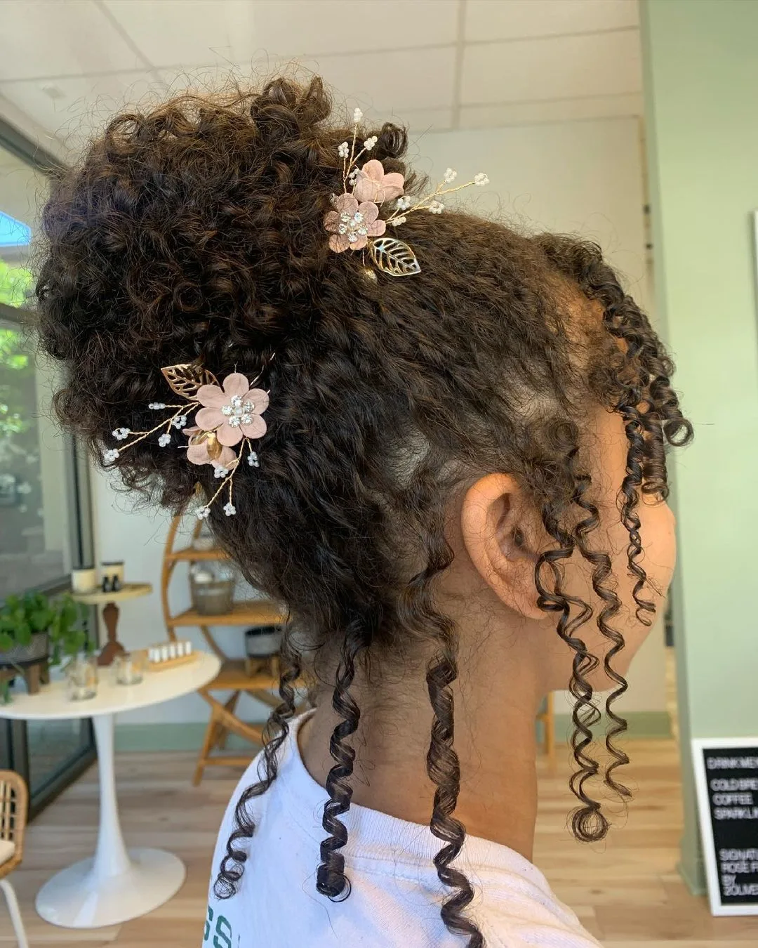 high curly bun with flower pins and bangs