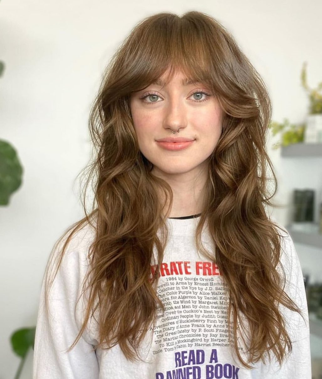 layered golden brown wavy hair with curtain bangs