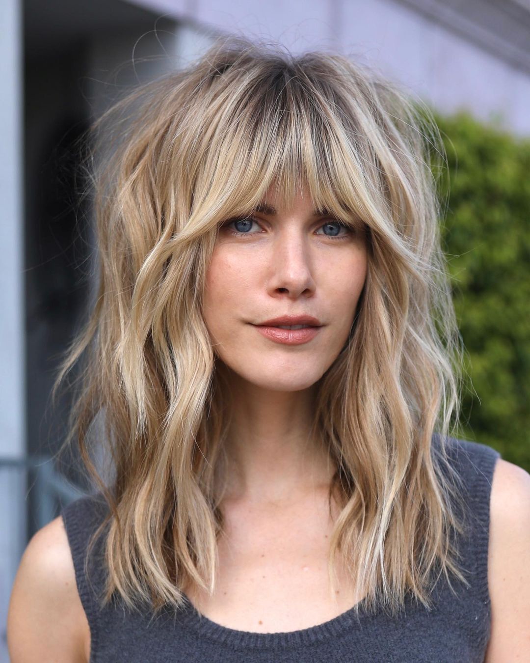 a woman with mid length wavy shag asymmetrical bangs hairstyle
