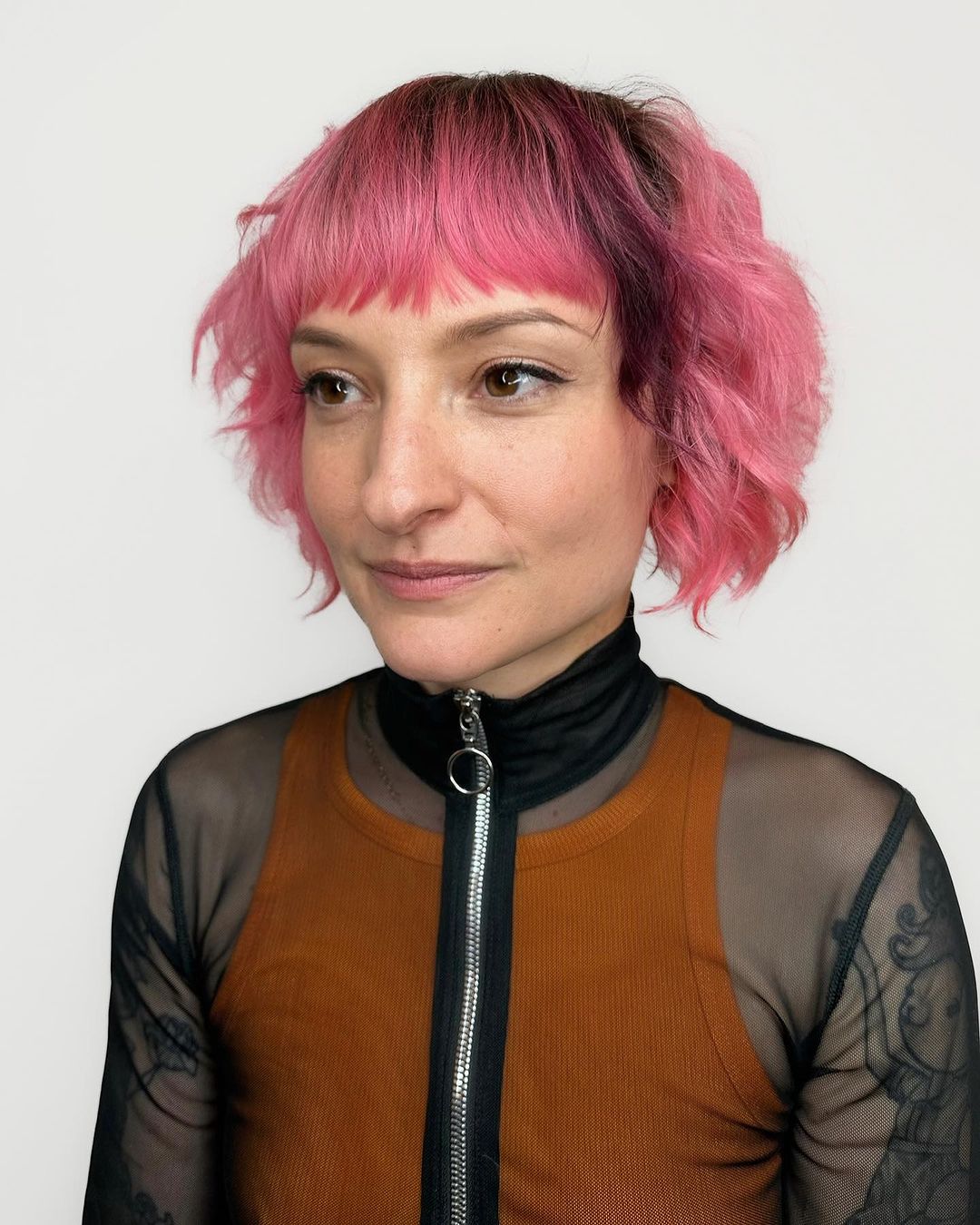 uma mulher com um cabelo desgrenhado cor-de-rosa pastel com franja