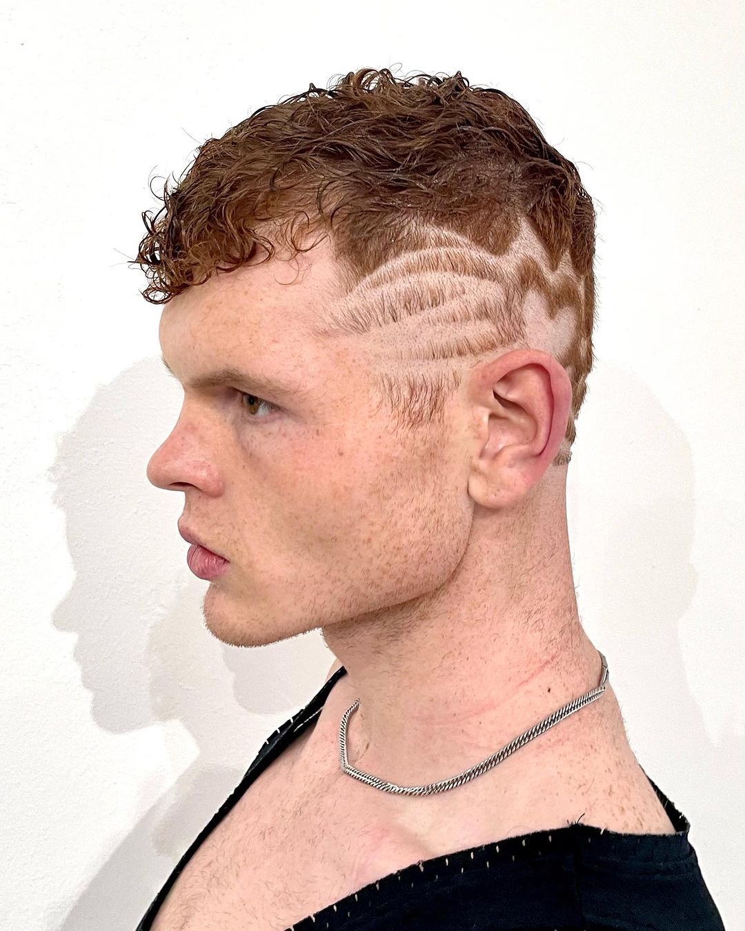 um homem com ondas curtas e tatuagens no cabelo