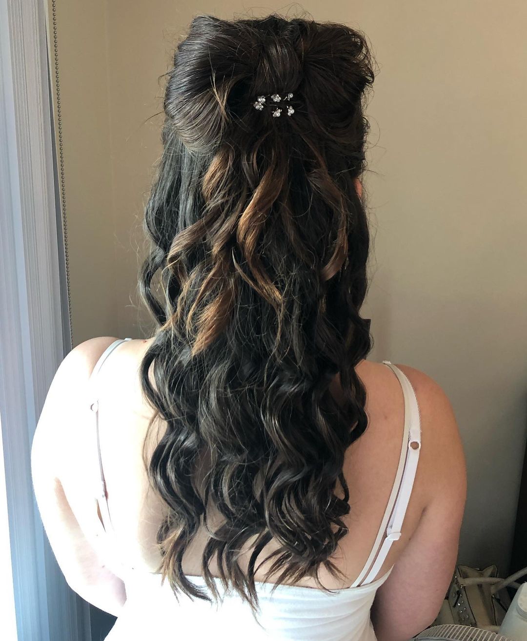 long brunette half up bow hairstyle with a flower pin