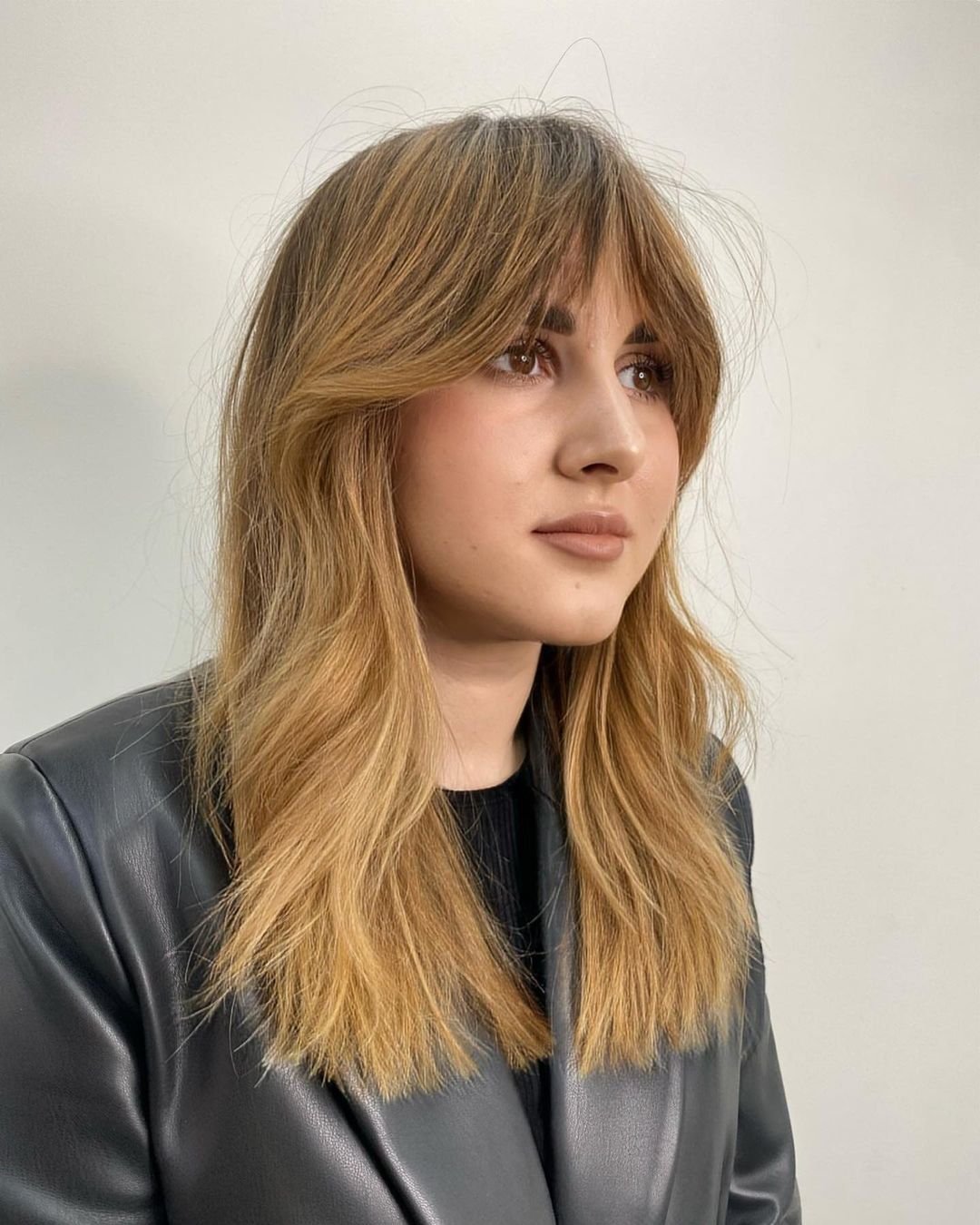 warm balayage and textured cut with french bangs