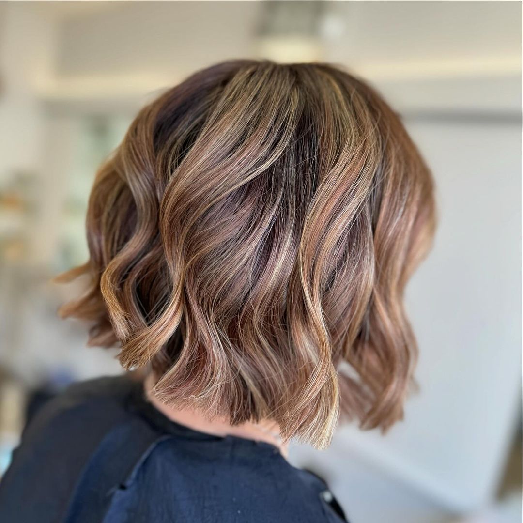 Balayage caramelo e arenoso num cabelo ondulado em ângulo