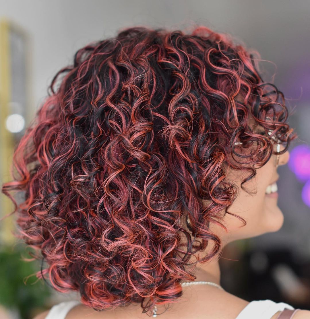 balayage vermelho-rosa em cabelo castanho encaracolado