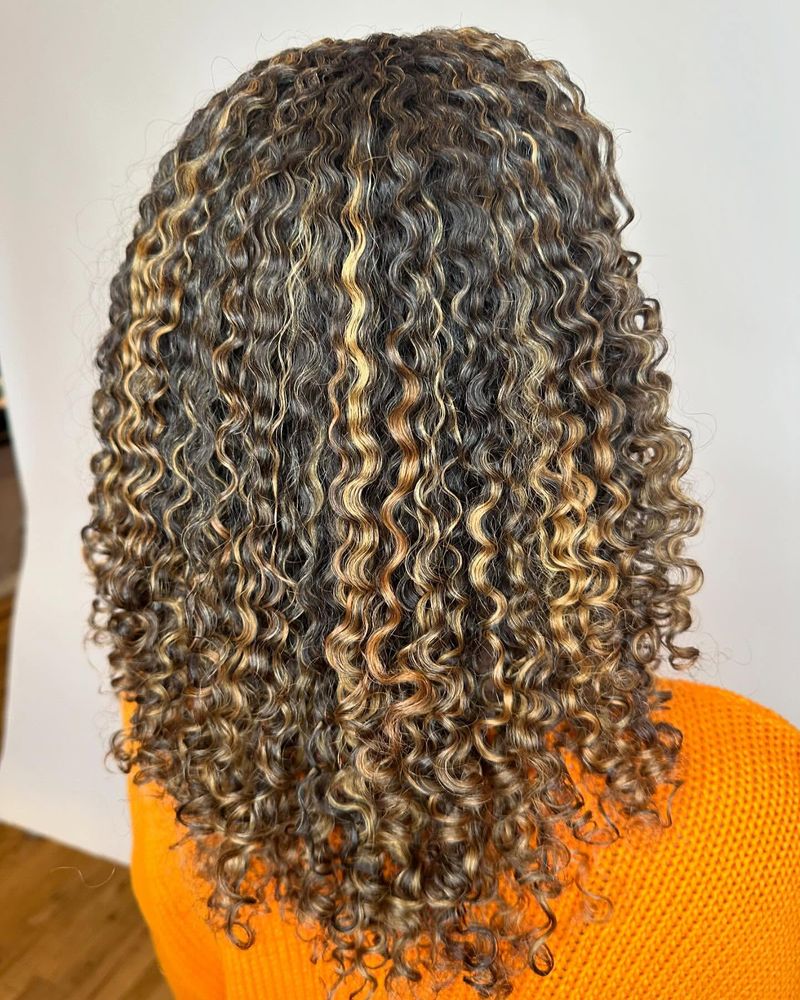 Cabelo encaracolado com madeixas bronzeadas