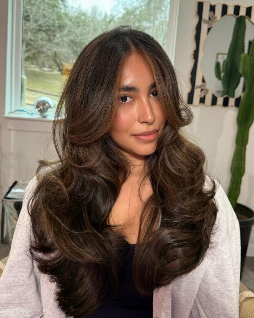 Woman using a curling wand to style wavy hair at home