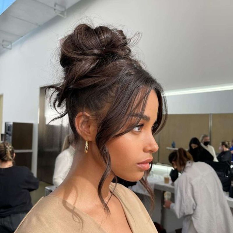 High Messy Bun with Face-Framing Tendrils