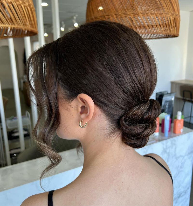 Sleek Low Bun with Face-Framing Tendrils
